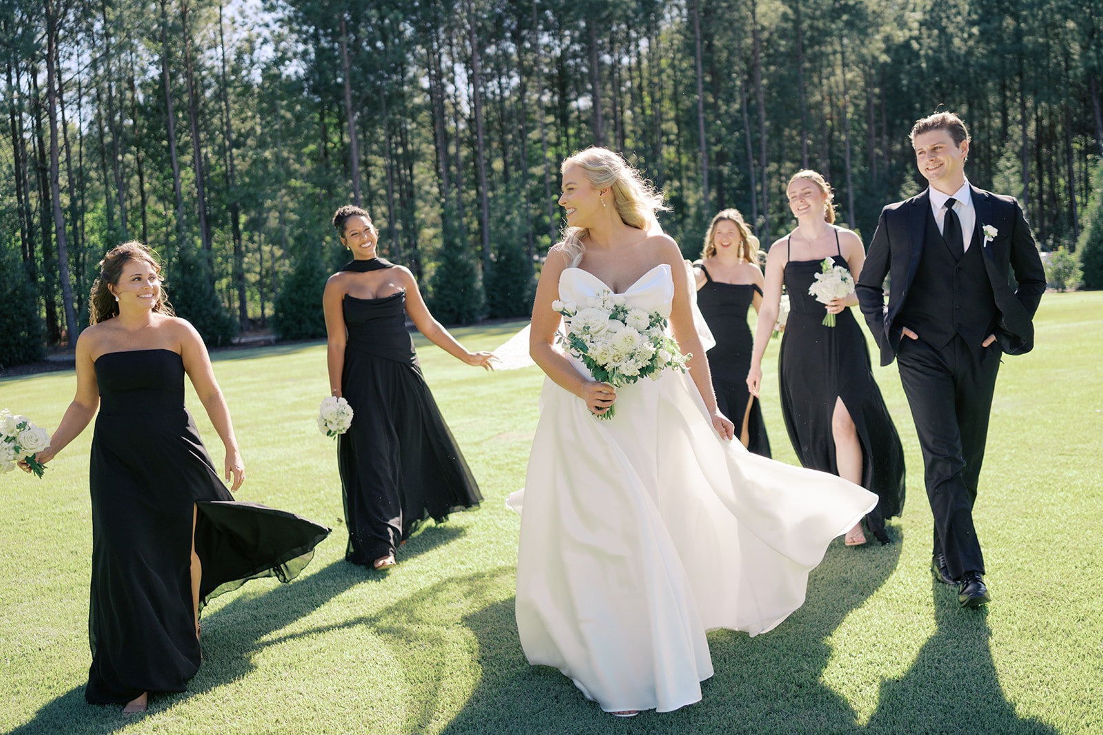 bride walking across the lawn with her bridal party at the bradford