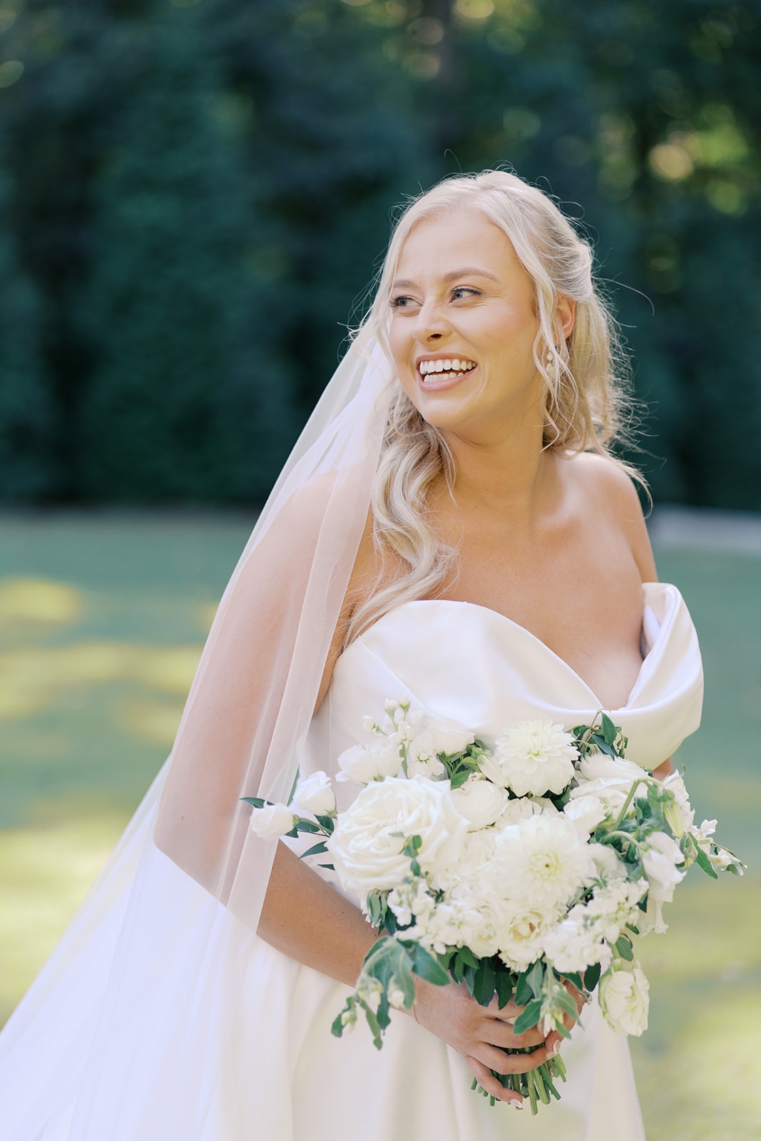 smiling bride holding a white bouquet before the ceremony