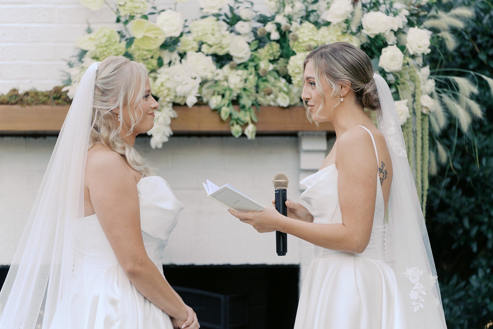 brides reading vows in front of the floral fireplace at the bradford