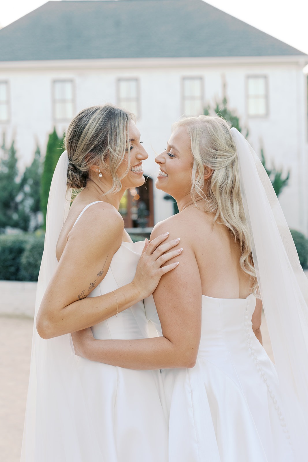 golden hour portrait of two brides in front of the bradford main house