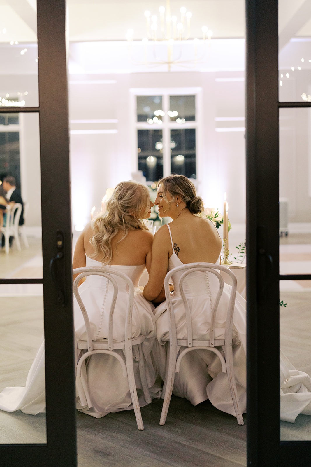 two brides sitting together at their reception at the bradford