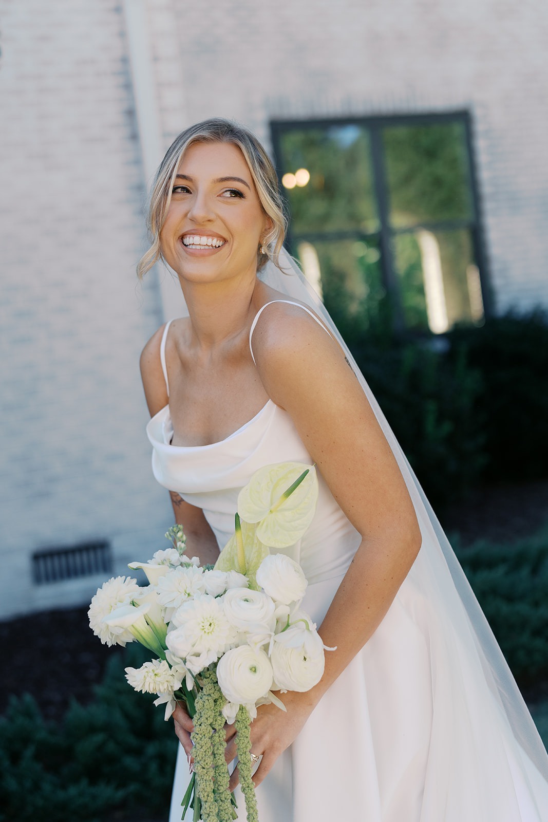 bride with white bouquet laughing outside the bradford in new hill nc